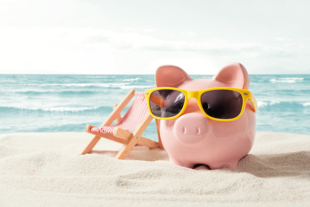 “Piggy bank wearing sunglasses on the beach next to a lounge chair, representing creative financial planning and fun at Professional Group Budget Day 2024.”